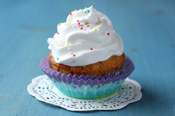 Obraz na płótnie Canvas Cupcake with white cream icing and candy sprinkles