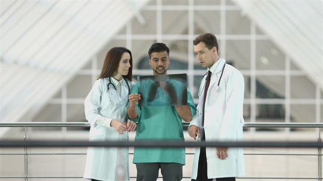 The doctors and the surgeon look at x-ray shot and discuss it
