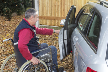 Man in a wheelchair in the fall next to their car
