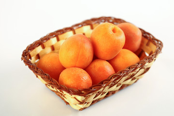 Ripe apricots in a wicker basket isolated on a white background