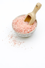 Fototapeta na wymiar bowl, bath salts in pink, spoon, grains of salt fallen isolated