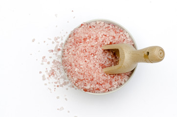 bowl, bath salts in pink, spoon, grains of salt fallen isolated