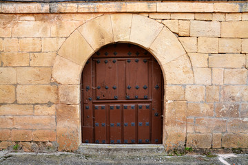 Fototapeta na wymiar puerta antigua de madera en casa tipica de piedra
