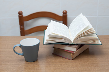 Some books and a cup of milk or coffe on a table