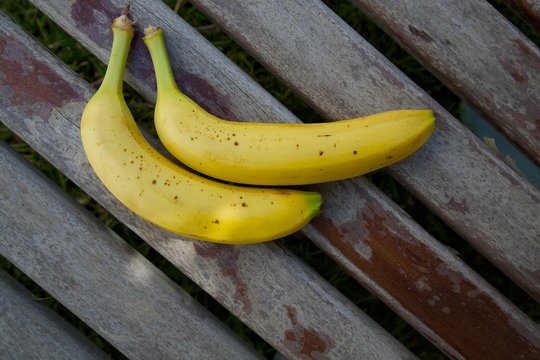 Two bananas on an old wooden surface