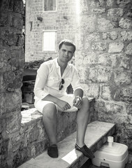 Fototapeta na wymiar Monochrome photo of handsome man sitting on old street