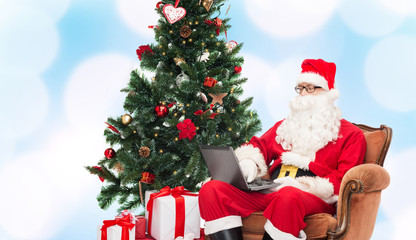 man in costume of santa claus with laptop