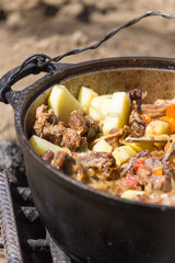 meat with potatoes in a cauldron on fire