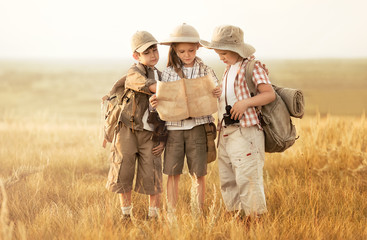Group of kids travelers read a map at sunset