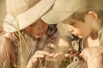 Two children explore insects and plants on earth