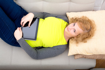 Junge Frau mit Tablet PC auf dem Sofa