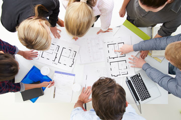 Overhead View Of Architects Discussing Plans In Office