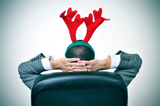 man with a reindeer antlers headband in his office chair