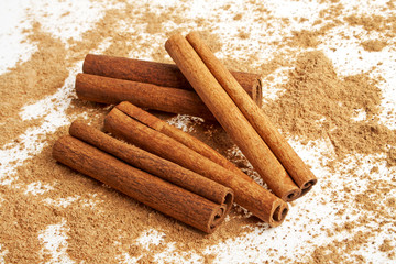 Cinnamon sticks with its dust around it over a white background