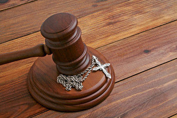 Mallet and silver cross isolated on the wooden background