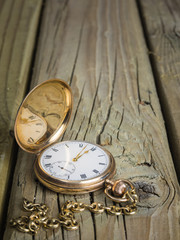 gold pocket watch and chain against  aged wood