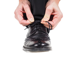 Closeup of male hands tying shoe laces on black leather shoes we