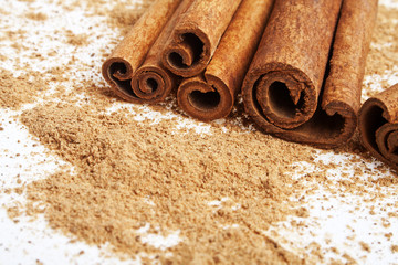 Cinnamon sticks with its dust around it over a white background