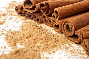 Cinnamon sticks with its dust around it over a white background