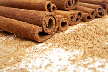 Cinnamon sticks with its dust around it over a white background