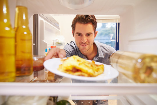 Man Looking Inside Fridge Full Of Unhealthy Food