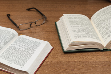 Open books and glasses on a wooden table