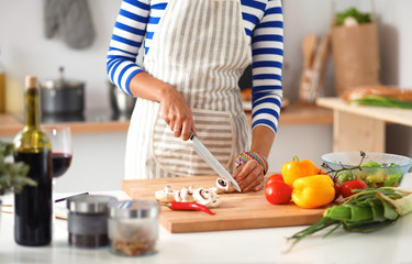 Young woman cutting vegetables in kitchen
