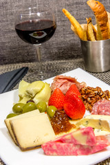 cheese, nut and meat plate with bread sticks and red wine