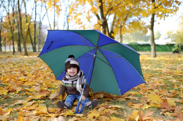 The kid with an umbrella plays in autumn park