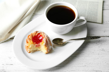 Cup of coffee with tasty cookie on color wooden background