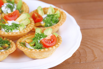 Fototapeta na wymiar Tartlets with greens and vegetables with sauce on plate on