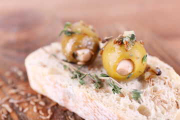 Green olives in oil with spices and bread on table close-up