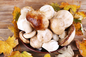 Wild mushrooms and autumn leaves in basket closeup