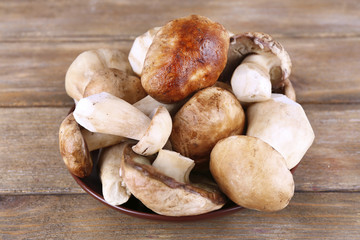 Wild mushrooms on plate on wooden background