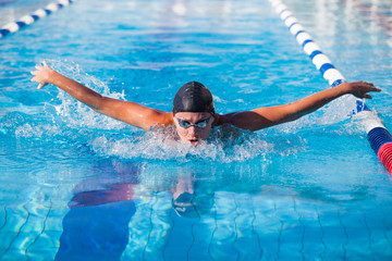 Butterfly swimmer in cap and glasses in the pool