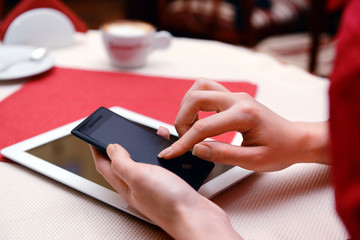 Woman with mobile phone and tablet computer in cafe shop
