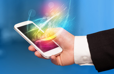 Hand holding smart phone with abstract glowing lines