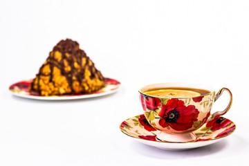 red flowered cup of tea on a background of a piece of cake