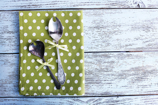 Metal spoons on green polka dot napkin on wooden background - Powered by Adobe