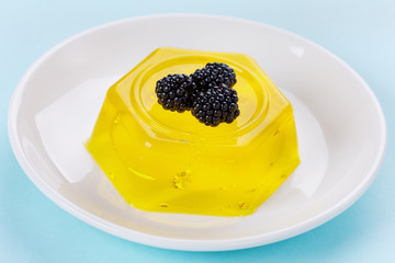 pineapple jelly pudding decorated blackberries on a white plate