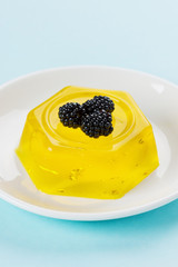 pineapple jelly pudding decorated blackberries on a white plate