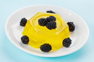 pineapple jelly pudding decorated blackberries on a white plate