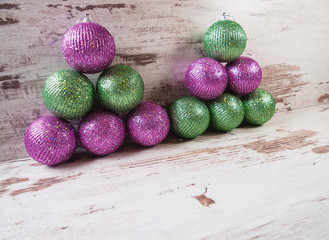 Pink and green christmas balls in a stack over wooden background