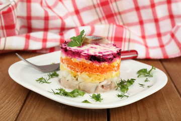 Russian herring salad on plate on wooden table background