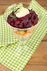 Russian herring salad in glass bowl on wooden table background