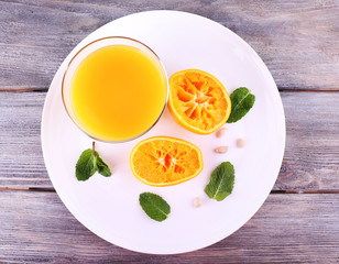 Glass of juice and ripe sweet tangerine on wooden table