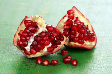 Juicy ripe pomegranates on green wooden table