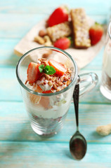 Healthy layered dessert with muesli and strawberries on table