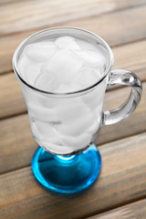Glass with ice cubes on wooden table