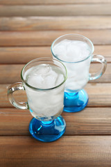 Glasses with ice cubes on wooden table